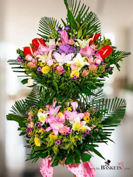 雙層開張花籃 (1) - 我們的熱情抱負花束展現了激情和活力，特色是一系列紅色、粉色和黃色玫瑰開張花籃，夾雜著精緻的紫色花朵和茂密的綠葉。